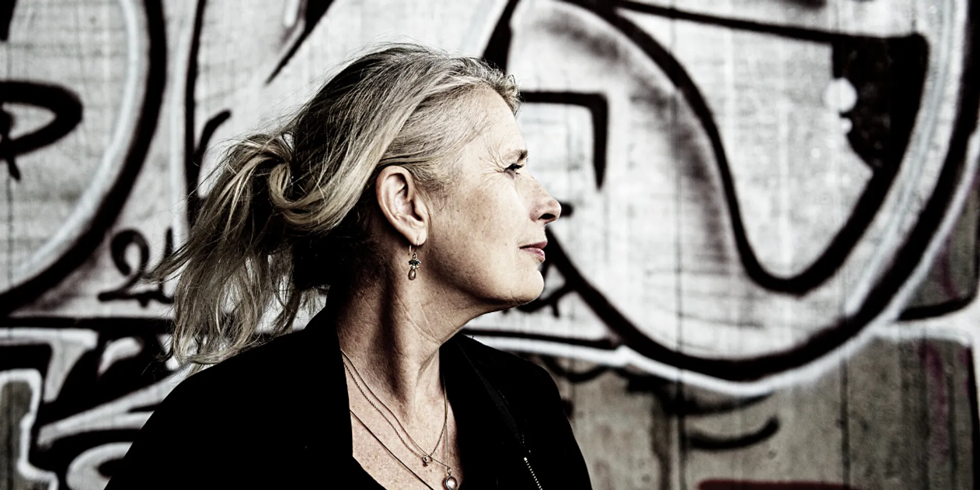 Caroline met op de achtergrond een betonnen muur met zwart-witte graffiti.