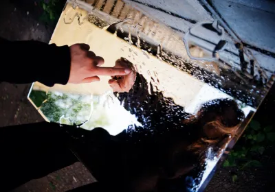 Een vrouwenvinger raakt een natte spiegel aan.